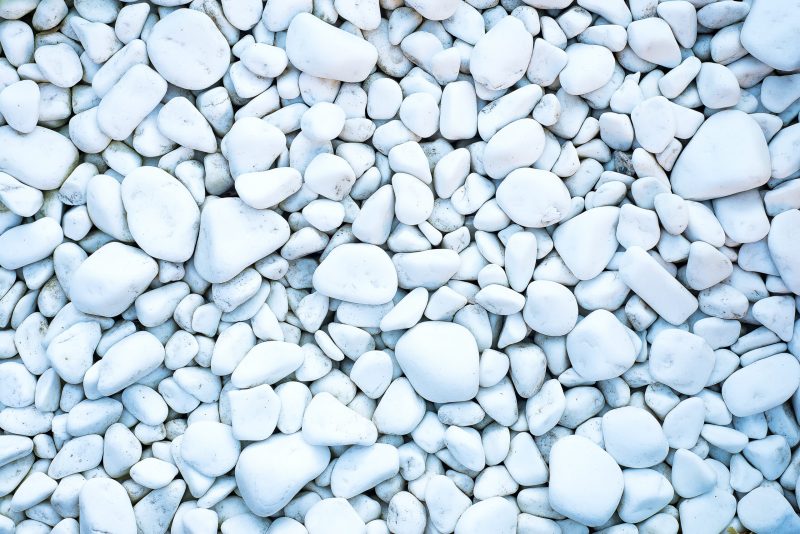 Naturally polished white rock pebbles background, top view